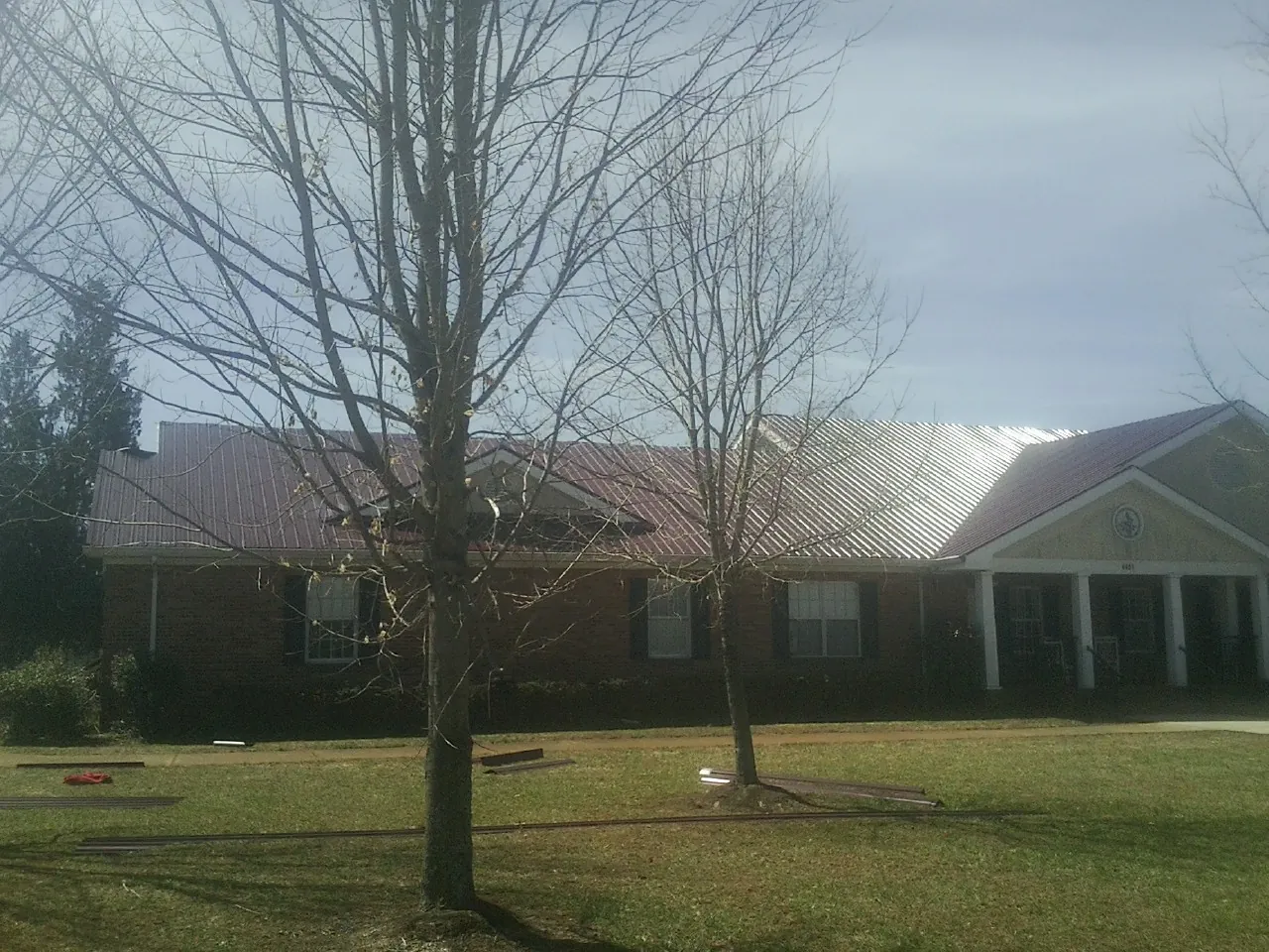 Red metal roof on a brick building seen from the front lawn in Du Quoin
