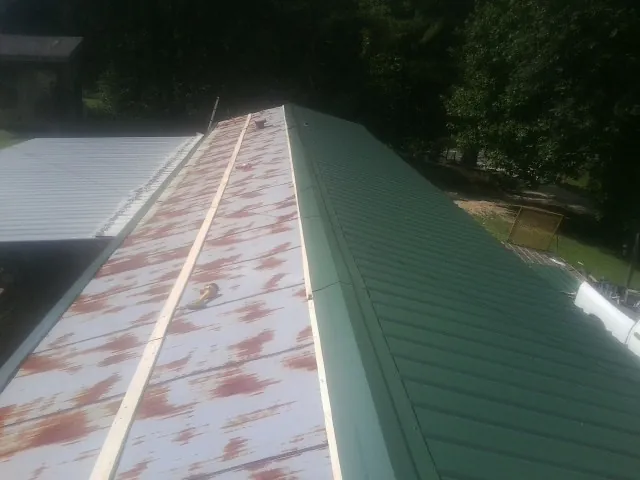 Old rusted panels beside newly installed green metal roofing — Wind Damage Roof Repair by Roofing Brothers in Du Quoin