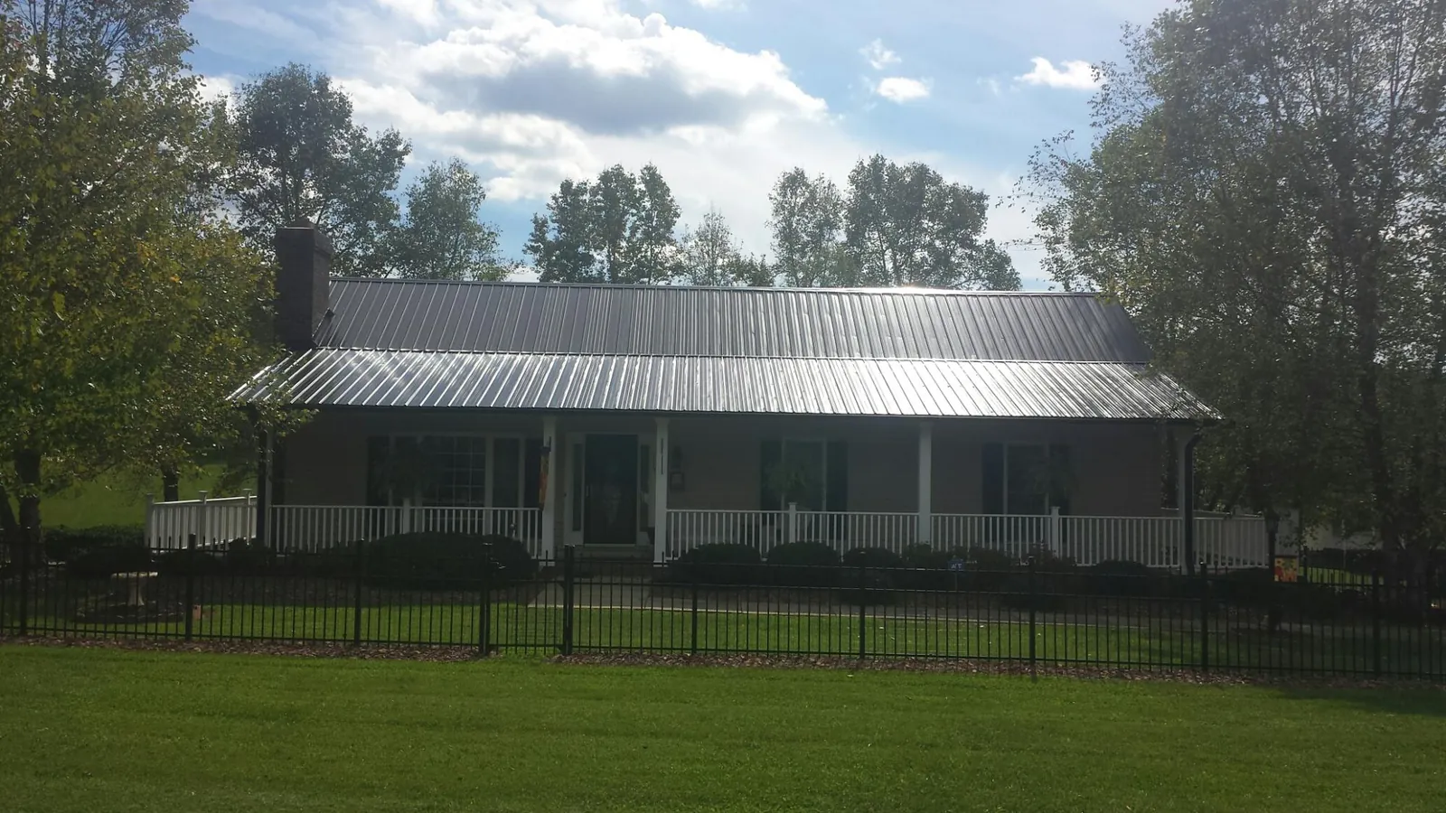 Gray metal roof on a brick ranch with a full width front porch — Gutter Guard Installation work by our crew in Du Quoin