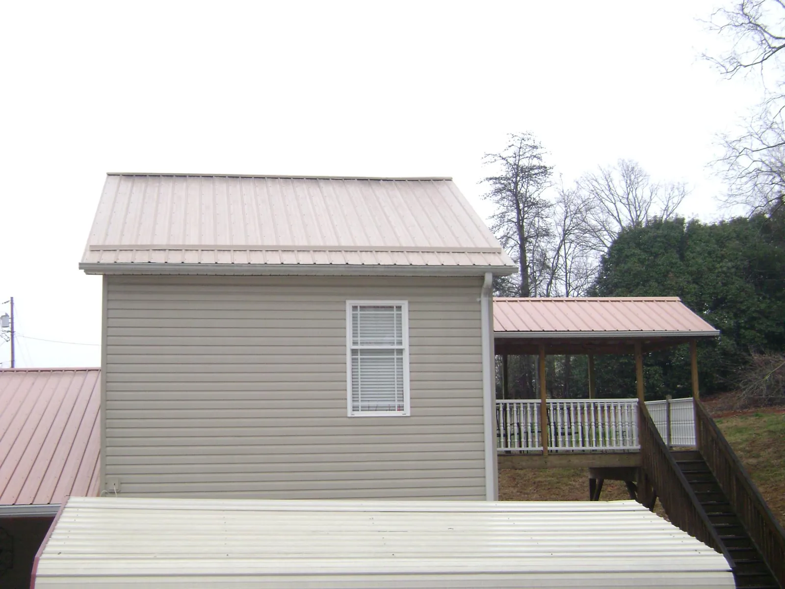 Tan metal roofs on a two story addition and attached porch, from a Roof Replacement job in Du Quoin