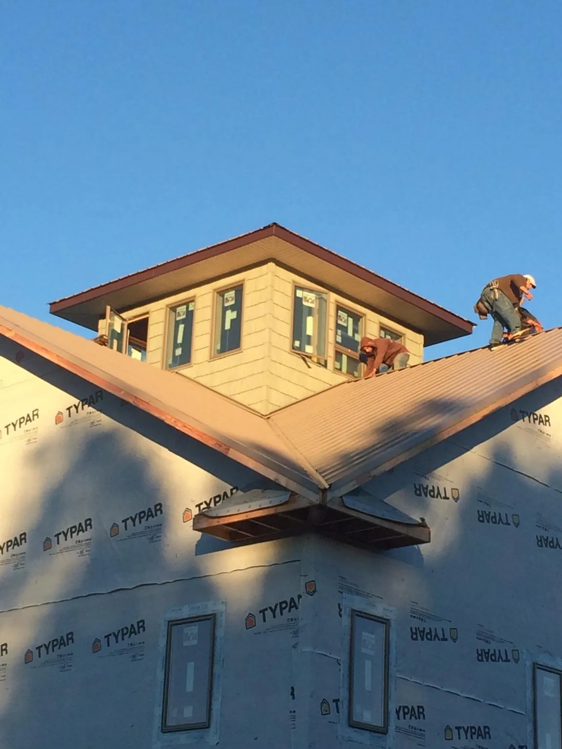Roofers working around a rooftop cupola on a new metal roof at sunset — Roof Waterproofing in Du Quoin by Roofing Brothers